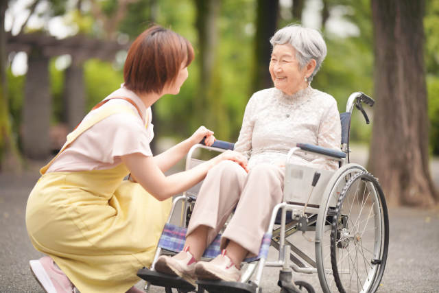 車いすの高齢者に話かている介護士
