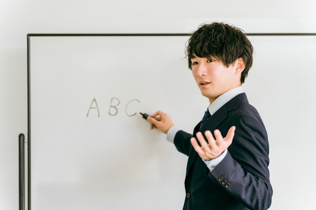 ホワイトボードの前で生活オリエンテーションについて説明する男性