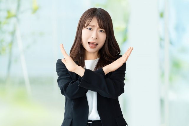 手でバツのポーズをしている女性