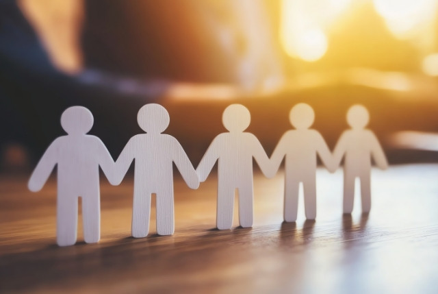 人材育成をイメージした切り取られた木製の人型が手を取り合っている