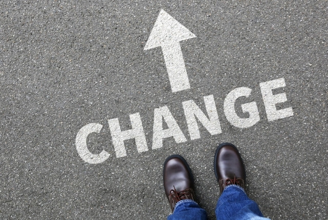 新制度への転換 地面に描かれた“CHANGE”と矢印の文字を前に立つ靴。就労ビザ取得や外国人雇用の制度変更、働き方の変化を象徴するイメージ