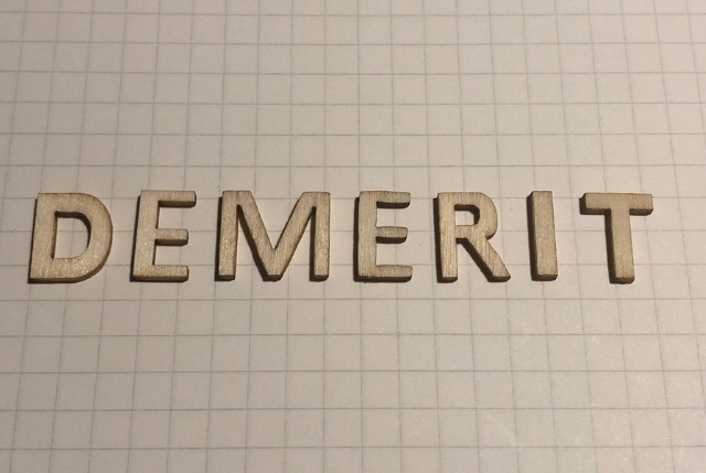 方眼紙の上に並べられた木製のアルファベットで『DEMERIT』と書かれた文字。ビジネスやサービスのデメリットを表すイメージ。