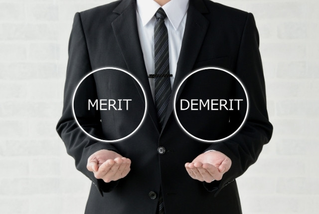MERITとDEMERITと書かれた文字を支えているビジネスマン